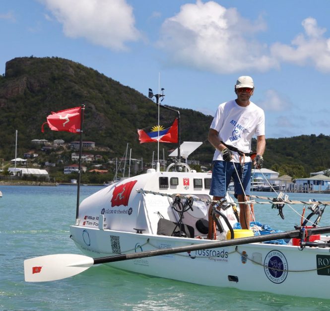 A rower on deck with the Isle of Man and Antigua flags
